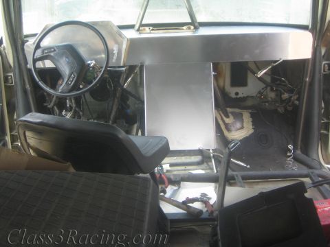 1990 Ford Bronco - Gutted cabin showing a fabricated aluminum dashboard, steering wheel and bare floor with mounted seats.