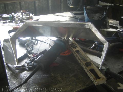 1990 Ford Bronco - welded aluminum dashboard piece sits on a shop workbench beside an angle grinder and hand tools.