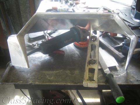 1990 Ford Bronco - bent aluminum dash panel on a cluttered workbench next to an angle grinder and a spirit level.