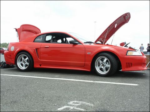2001 Mercury Grand Marquis - A red Ford Mustang GT is parked with its hood and trunk open, displaying its side profile.