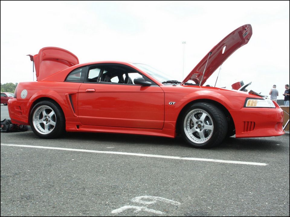 Red Ford Mustang GT with hood and trunk open, side view