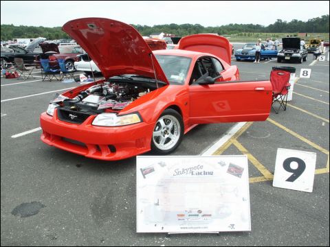 2001 Mercury Grand Marquis - Red Ford Mustang on display at a car show, hood and doors open to show the engine and interior.