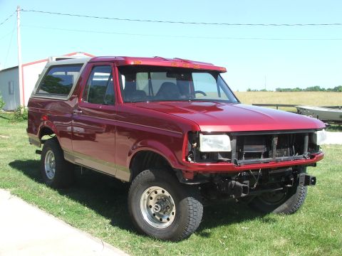 1994 Ford Bronco - This red Ford Bronco SUV, likely from the early to mid-1990s, is shown with its front end partially disassembled.