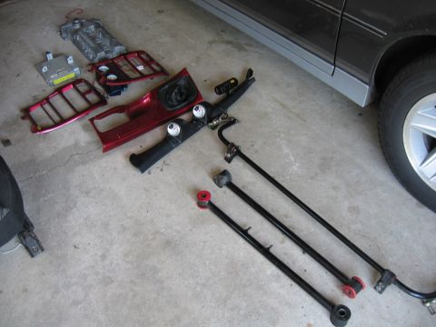 1993 Ford Probe - Various car parts, including interior trim and suspension components, laid out on a concrete surface.
