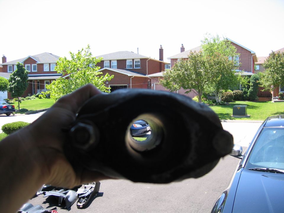Exhaust pipe part held up to view a blue car through its opening