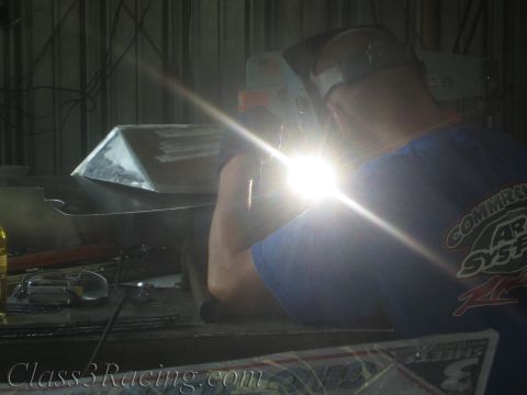 1990 Ford Bronco - welder leans into an aluminum piece as the welding arc throws a brilliant star of light across the shop.