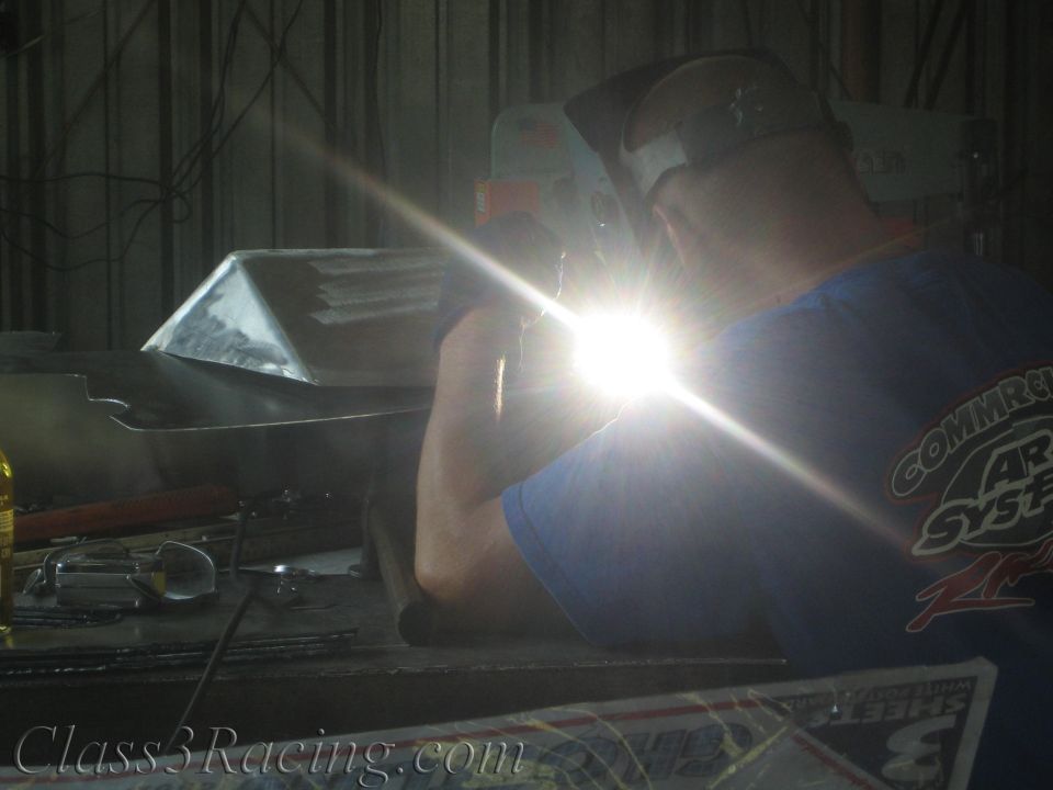 Welder in helmet welding aluminum with a brilliant arc flare