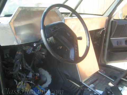 1990 Ford Bronco - Ford steering wheel and unpainted aluminum dash panel above a mass of exposed wiring in a gutted vehicle.