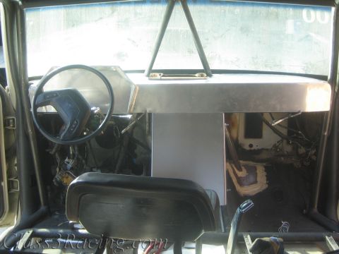 1990 Ford Bronco - Gutted vehicle cabin showing a fabricated aluminum dashboard, steering wheel and front bench seat in daylight.