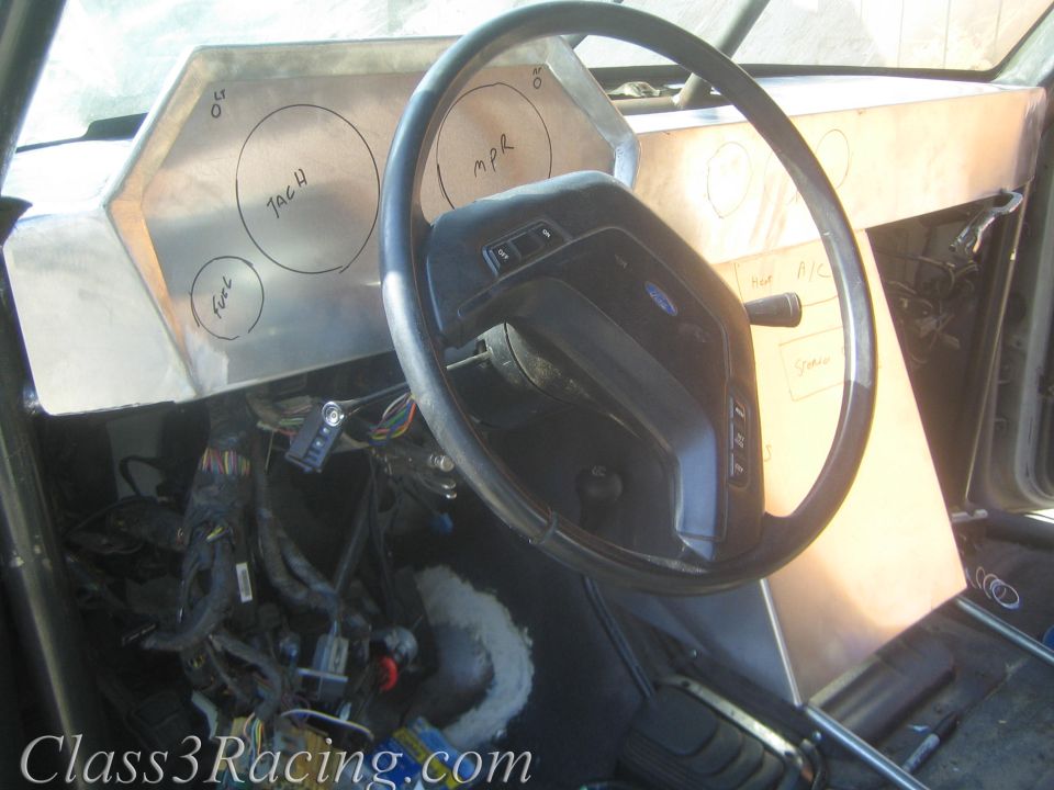 Race vehicle interior with steering wheel and aluminum dash panel with circle gauge cutouts