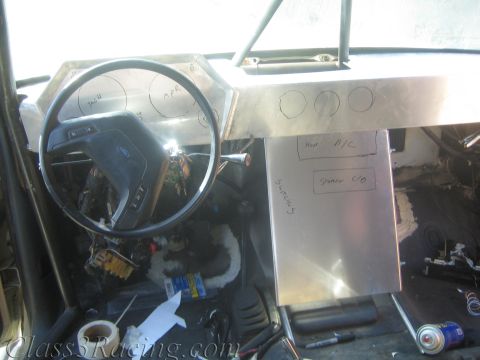 1990 Ford Bronco - wide view of a gutted race vehicle cab showing the steering wheel, fabricated aluminum dash and tools scattered on the floor.