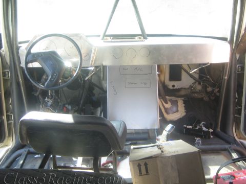 1990 Ford Bronco - Interior of a stripped race vehicle with a bench seat, fabricated aluminum dash and a cardboard box resting on the floor.