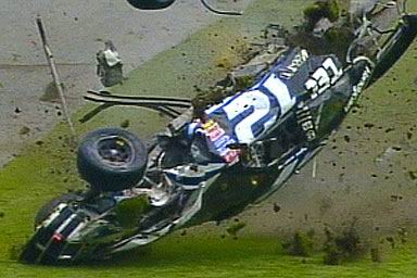 1981 Ford Bronco - Race car #27 is overturned on the track after an incident, with grass and debris around it.