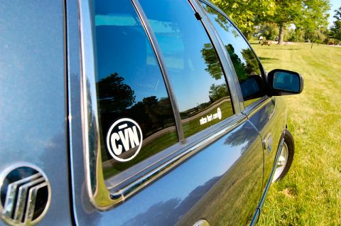 1985 Mercury Grand Marquis - A blue Mercury sedan is parked on a grassy field with trees in the background.
