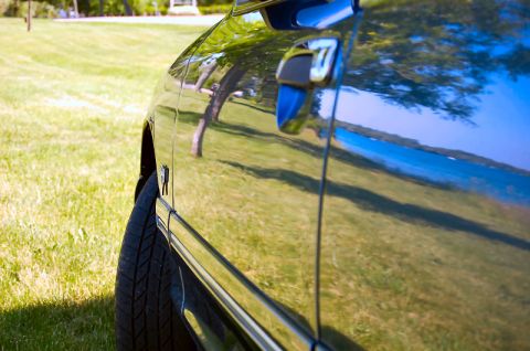 1985 Mercury Grand Marquis - Side view of a car's door and tire, with reflections on the glossy paintwork.