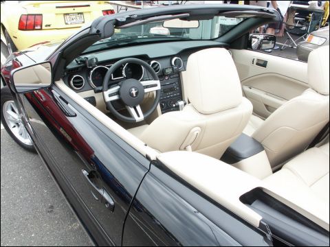 2001 Mercury Grand Marquis - The interior of a black convertible is shown, tan leather seats and a Mustang emblem on the steering wheel. Another vehicle is visible in t…