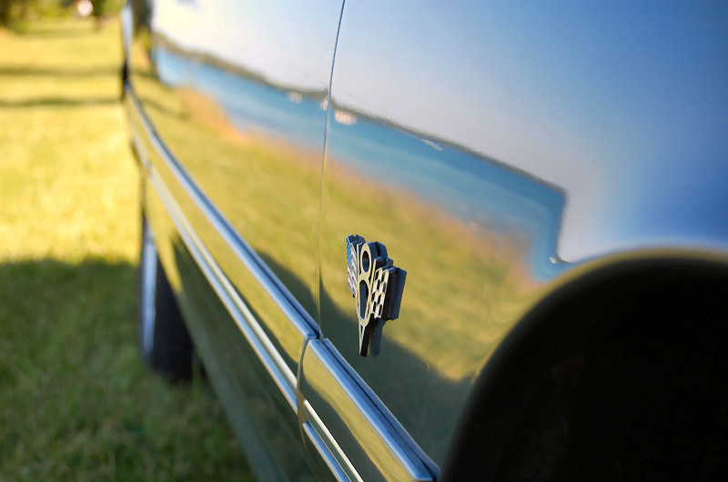 Dark blue car door with chrome trim and a checkered flag badge