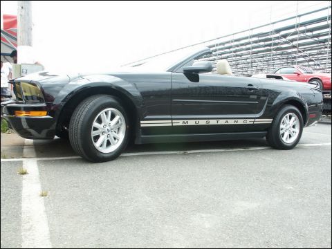 2001 Mercury Grand Marquis - A black convertible Mustang is parked at an outdoor event, with another red car visible in the background.