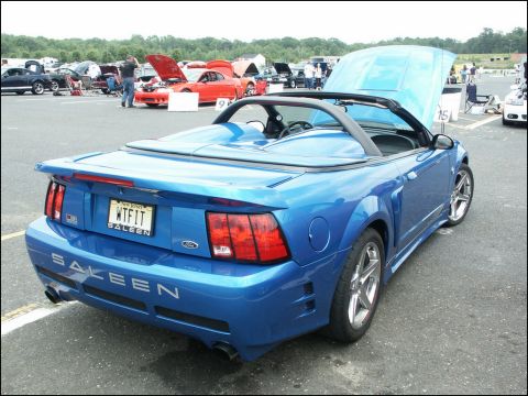 2001 Mercury Grand Marquis - Blue Saleen convertible at a car show, hood open on a red car in the background.