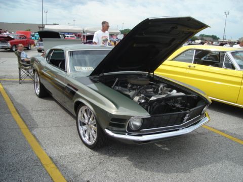 1992 Ford Crown Victoria - A classic Mustang is displayed at an outdoor car show with its engine exposed.