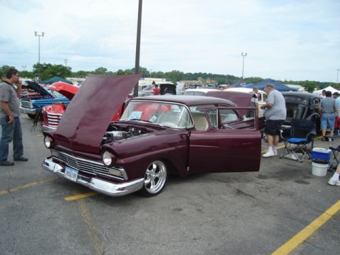 1992 Ford Crown Victoria - A maroon 1956 Ford sedan is displayed with its hood and driver door open at an outdoor car show.