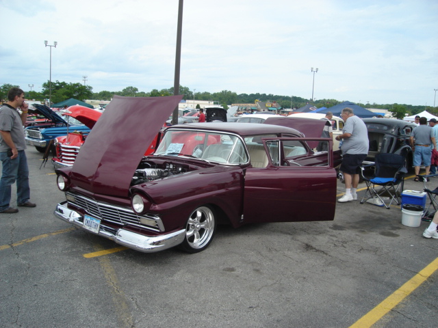 Maroon 1956 Ford sedan, hood and driver door open, chrome grille, custom wheels, parked at car show