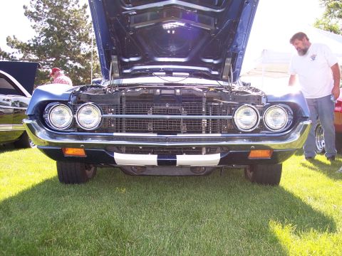 1972 Ford Ranchero - A man looks at the engine of a blue 1969 Ford Torino GT at a car show.
