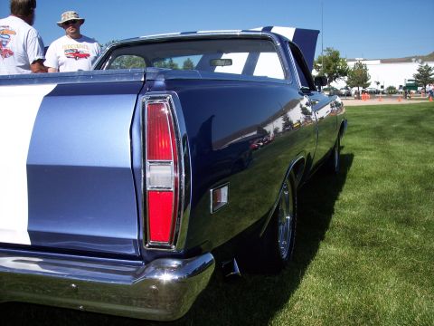 1972 Ford Ranchero - A blue 1972 Ford Ranchero with white racing stripes is parked on grass.