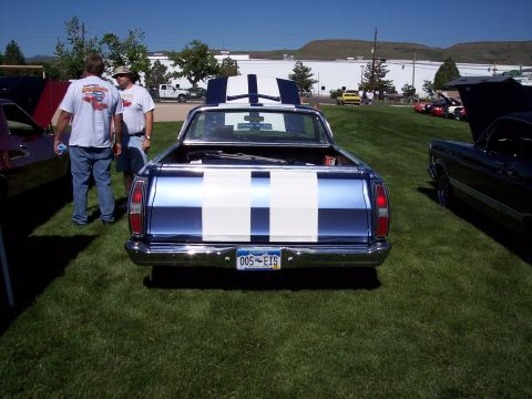 1972 Ford Ranchero - A blue 1972 Ford Ranchero with distinctive white racing stripes is parked on a grassy field, alongside other vehicles.