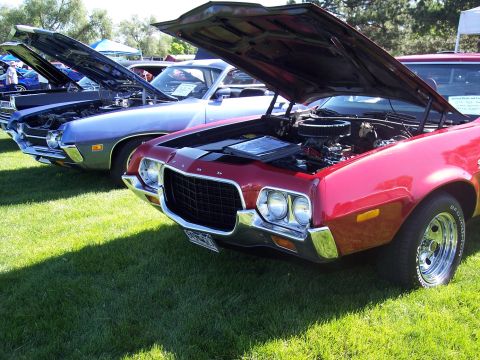 1972 Ford Ranchero - A red 1972 Ford Ranchero is parked on grass with its hood open, alongside other vehicles.