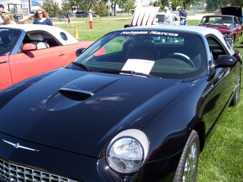 1972 Ford Ranchero - A black convertible with a white top and a hood scoop is parked on the grass next to a red convertible.
