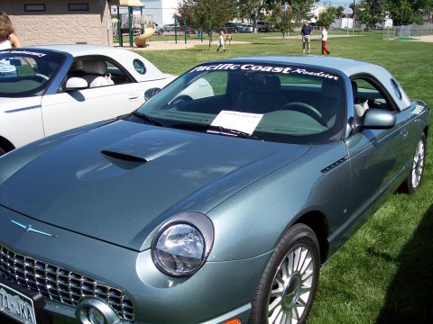 1972 Ford Ranchero - A teal Ford Thunderbird with a 'Pacific Coast Roadster' banner on the windshield is parked on grass next to another convertible.
