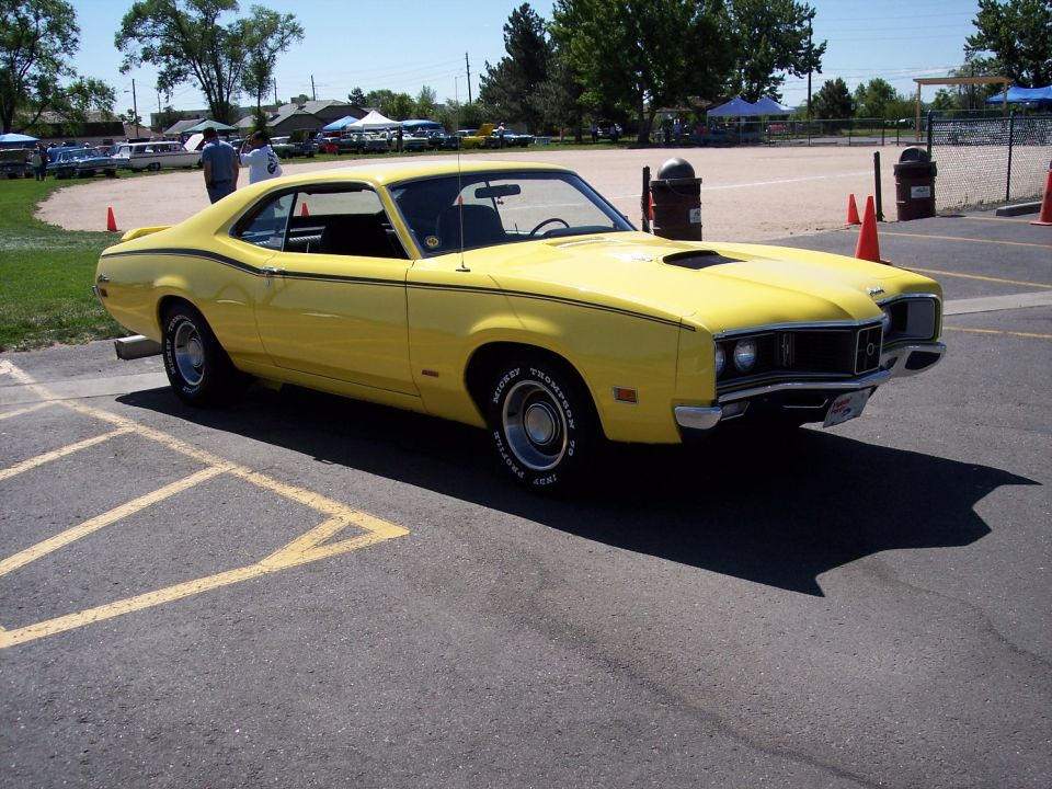 Yellow 1970 Mercury Cougar XR7 coupe with black racing stripes and hood scoop