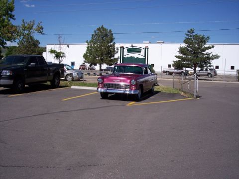 1972 Ford Ranchero - A pink 1955 Chevrolet Bel Air is parked in a lot next to a black pickup truck.