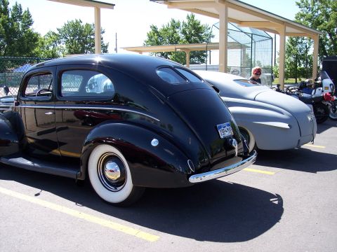 1972 Ford Ranchero - Rear view of a black 1939 sedan with whitewall tires, parked next to another car.