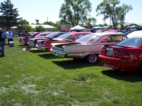 1972 Ford Ranchero - A collection of vintage automobiles are displayed on a sunny day, with a modern red car parked closest to the viewer.
