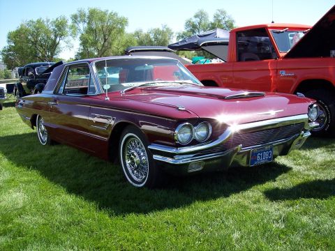 1972 Ford Ranchero - A maroon 1961 Ford Thunderbird is parked on grass next to a red Ford Bronco.