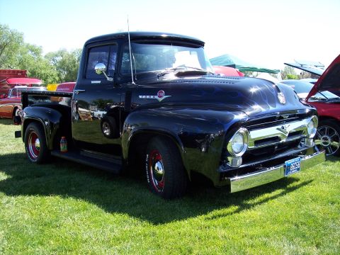 1972 Ford Ranchero - A black 1953 Ford pickup truck with custom flame paint sits on a grassy field next to other vehicles.
