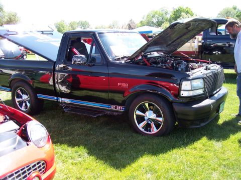 1972 Ford Ranchero - Black 1992 Ford F-150 pickup truck with hood open, parked on grass at an event.