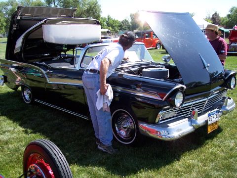 1972 Ford Ranchero - A black 1957 Ford Fairlane convertible is examined by a man, with another vehicle visible in the background.