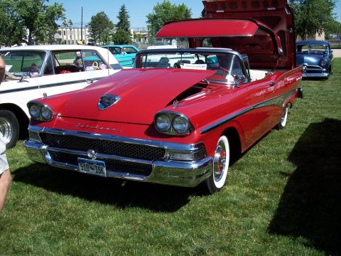 1972 Ford Ranchero - A bright red 1958 Ford Fairlane convertible is displayed with its hood and trunk open at an outdoor event.