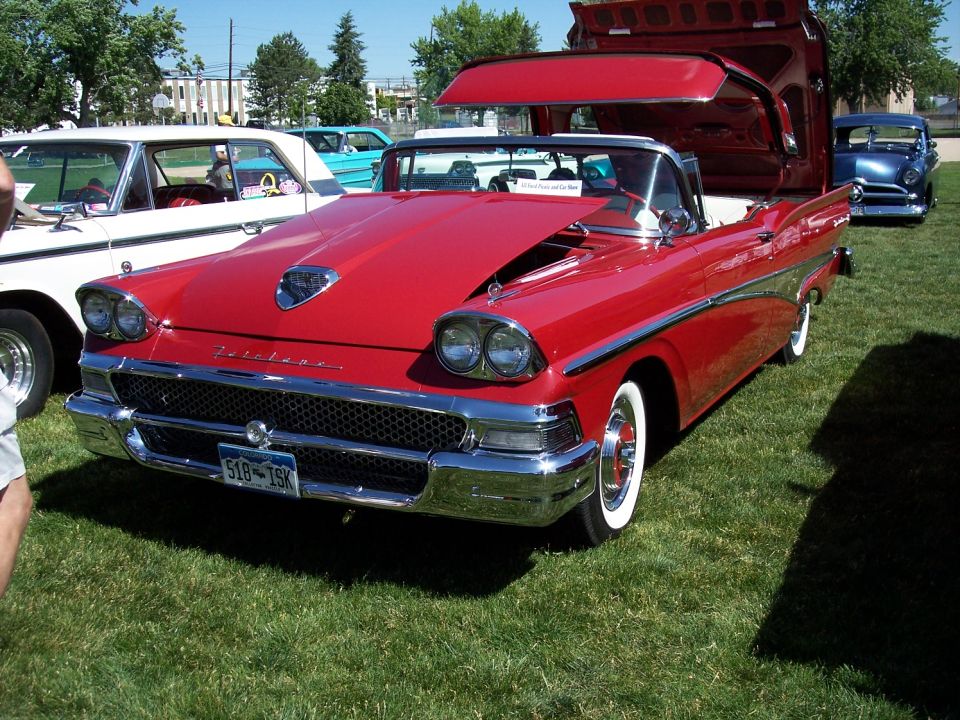 Red 1958 Ford Fairlane convertible with hood open, showing chrome grille and dual headlights