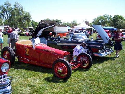 1972 Ford Ranchero - A red race car and a black convertible are parked on grass at an outdoor event.