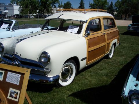 1972 Ford Ranchero - A classic wood-paneled station wagon is displayed on a grassy field with other vehicles.