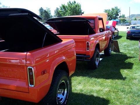 1972 Ford Ranchero - Two Ford Bronco pickup trucks are displayed with their bed covers open at an outdoor event.