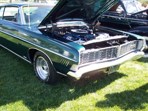 1972 Ford Ranchero - A green 1970 Ford car with its hood open, parked on a grassy lawn next to another vehicle.