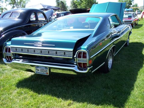 1972 Ford Ranchero - A green 1970 Ford Torino GT is parked on grass with its hood open, alongside other vehicles.