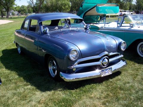 1972 Ford Ranchero - Blue 1950 Ford Custom sedan displays custom flames and chrome wheels at an outdoor car show.