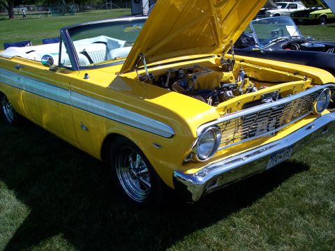 1972 Ford Ranchero - A yellow convertible with its hood open, parked on grass at a car show with other vehicles visible.
