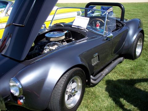 1972 Ford Ranchero - A dark gray convertible with its hood open, revealing the engine, sits on a grassy field next to a yellow car.